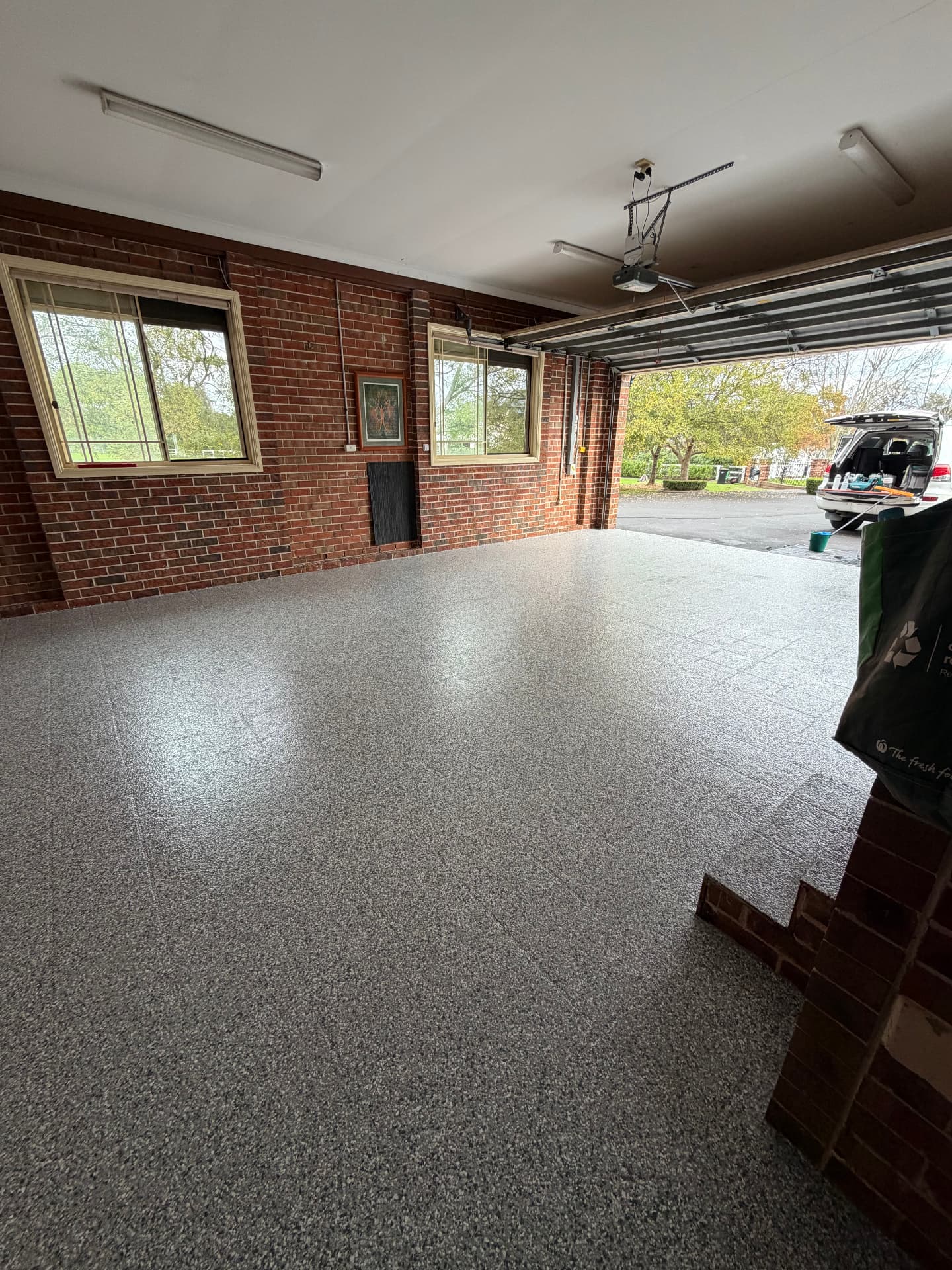 Brick garage with a seamless grey flake epoxy floor running out to the driveway